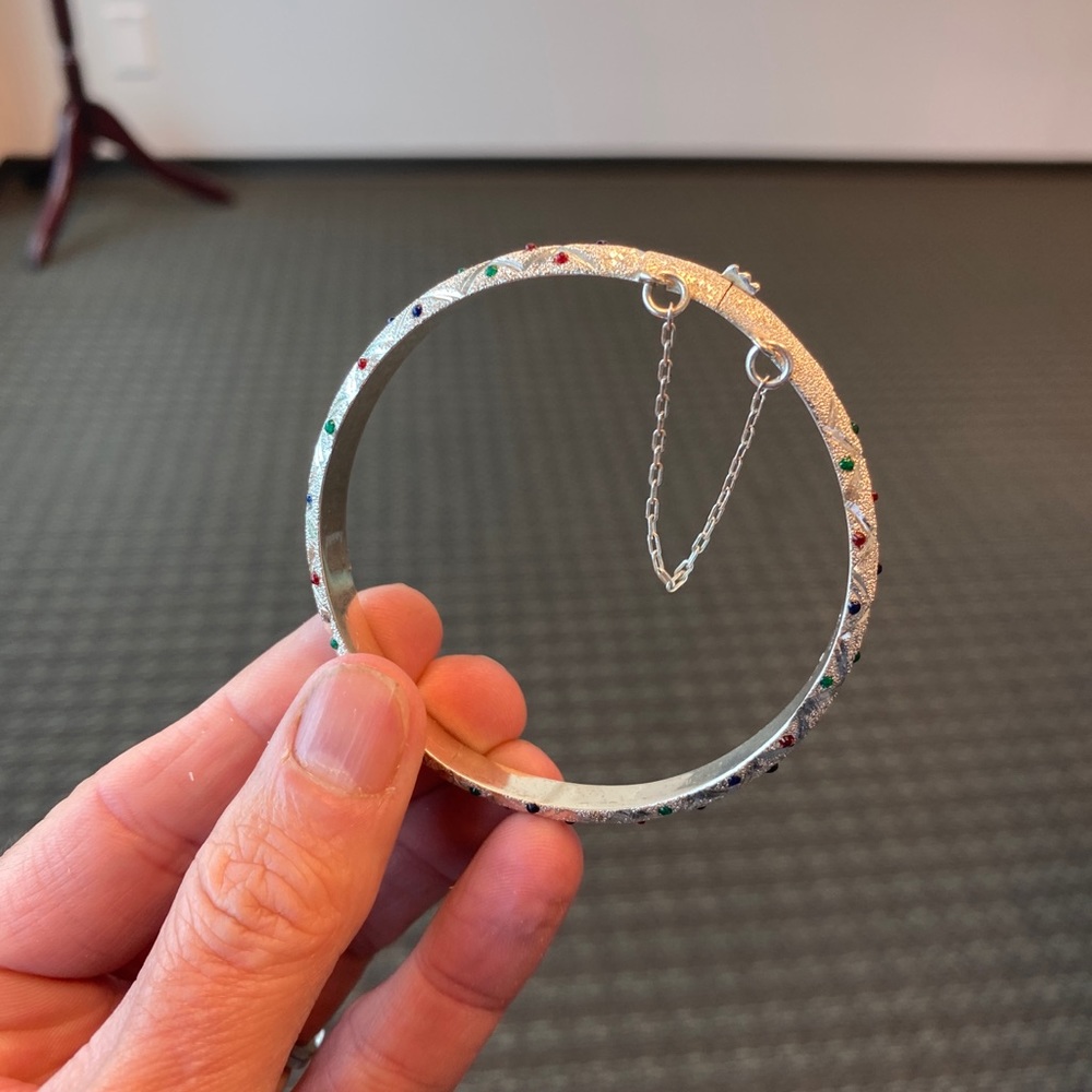 Sterling silver hinged bangle with multi color accents.